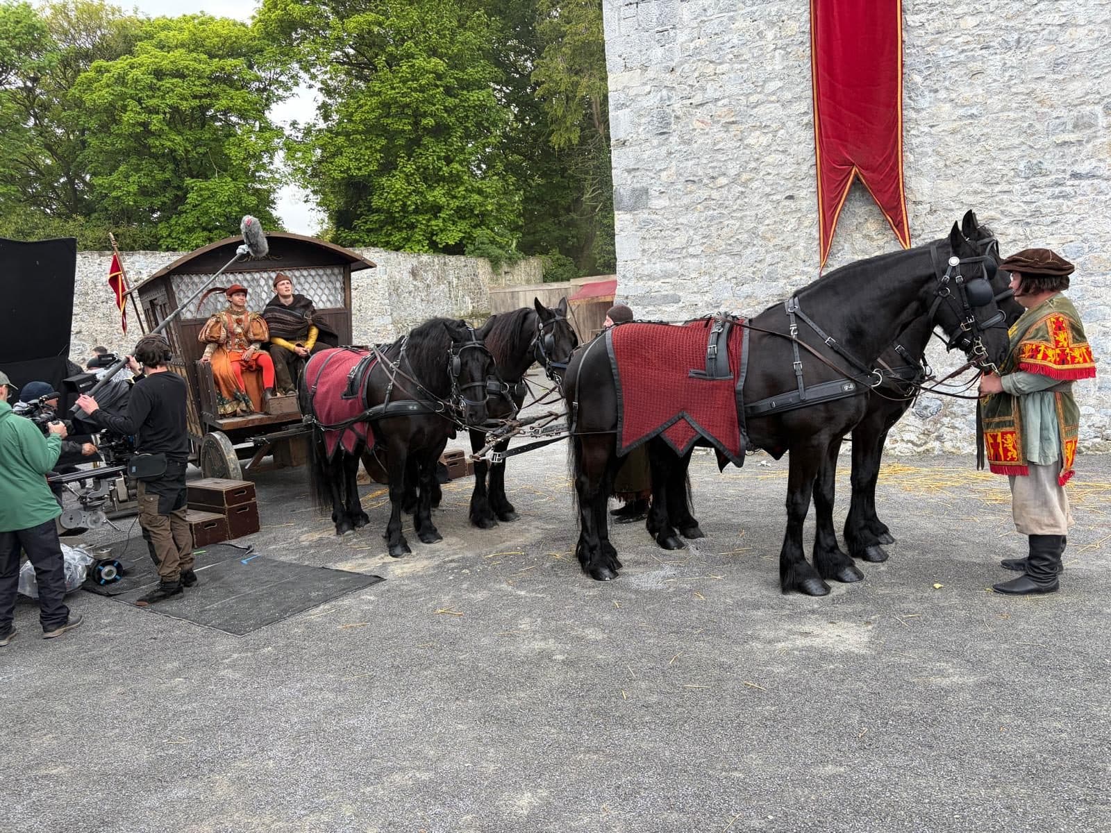 Camera crew filming a horse-drawn wagon in a castle courtyard